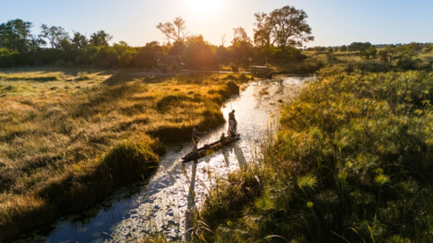 A mokor moves through a Okavango Delta waterway at sunset
