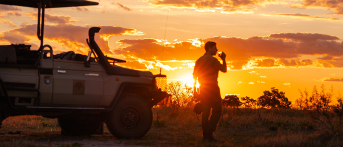 A guest on safari enjoys a sundowner drink 