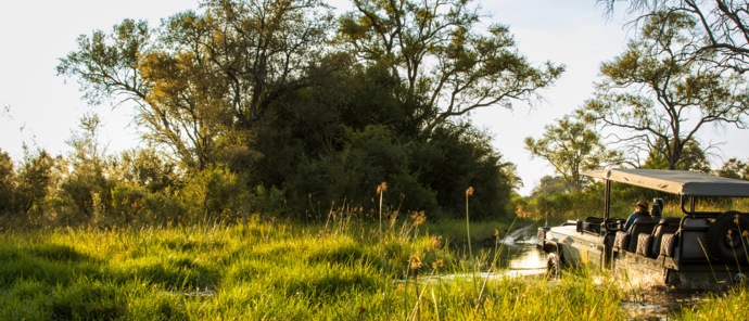 A game drive vehicle makes its way across a river of teh Okavango Delta