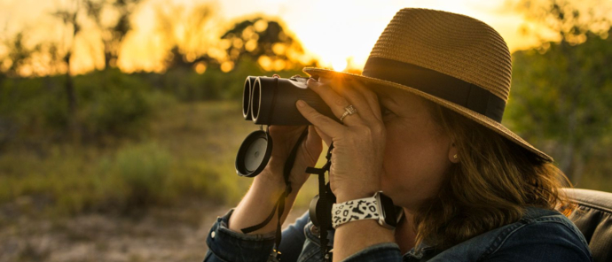 A guests on safari views the Okavango Delta through binoculars